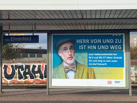 Großflächenplakat mit Männerportrait am Bahnhof Köln-Ehrenfeld – Kampagne für den Nahverkehr Rheinland, fotografiert von nonverbal | businessfotografie.